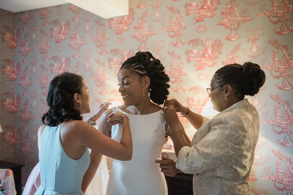 Loved ones helping the bride adjust her dress