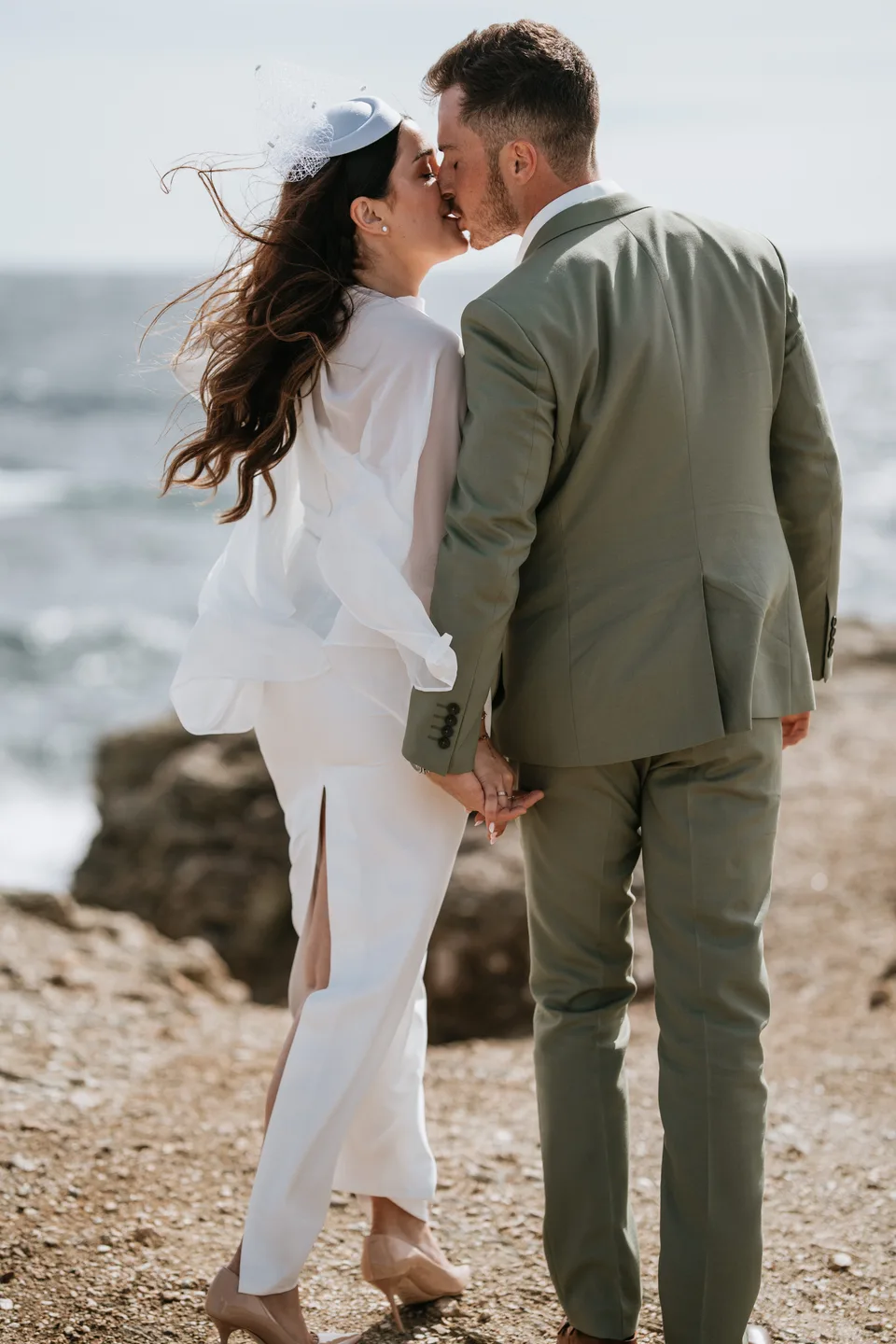 Newlyweds holding hands facing the sea