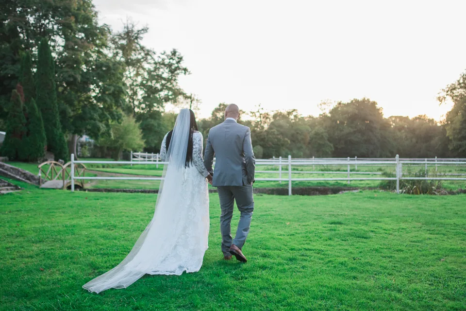 Newlyweds walking towards the sunlight in the garden