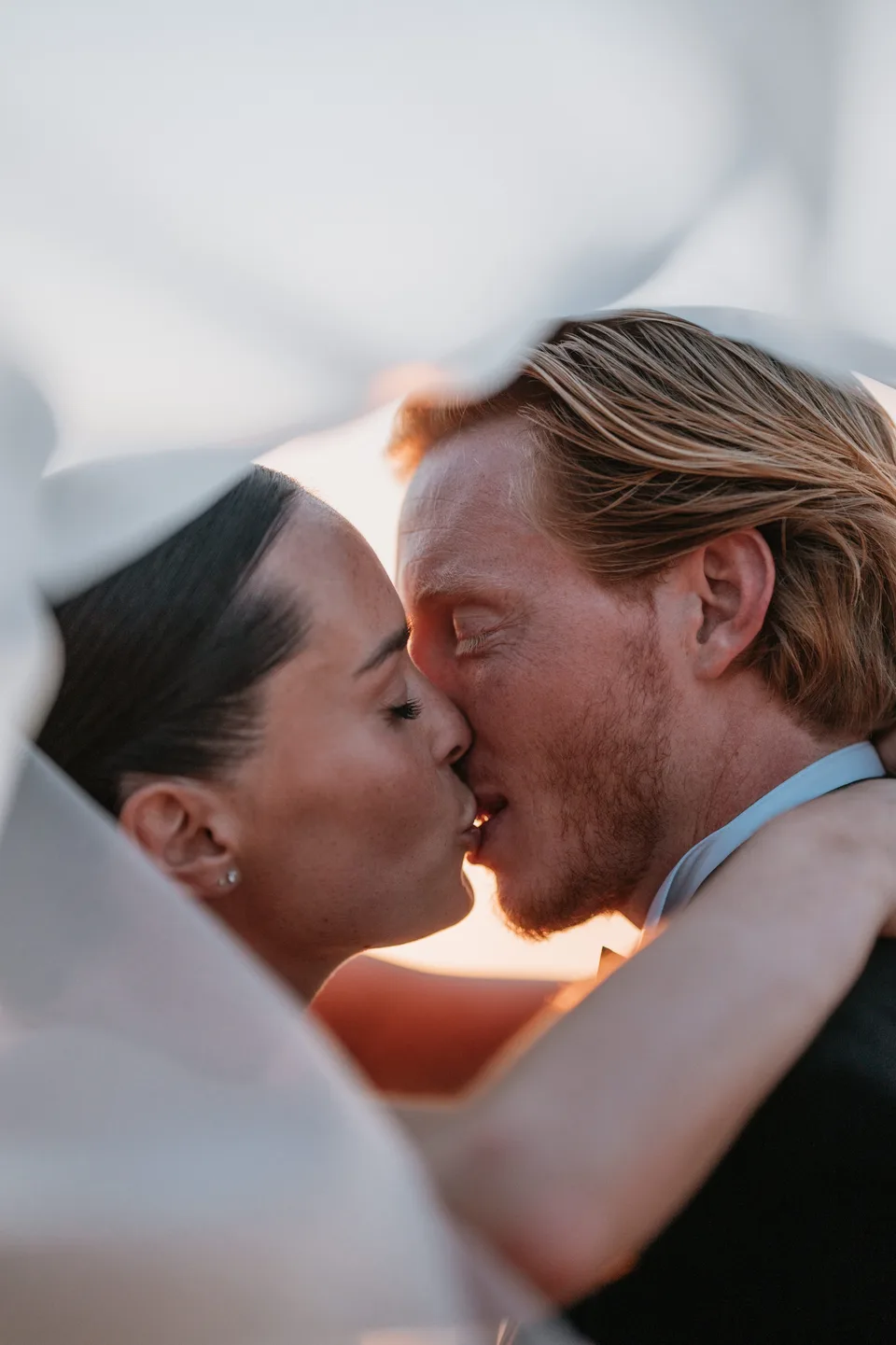Newlyweds kissing beside the sea