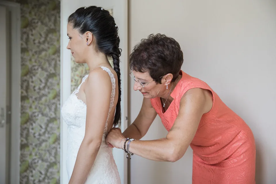 A loved one adjusting the bride’s dress