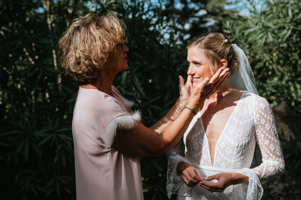 A hand touching the bride’s face in the sunlight