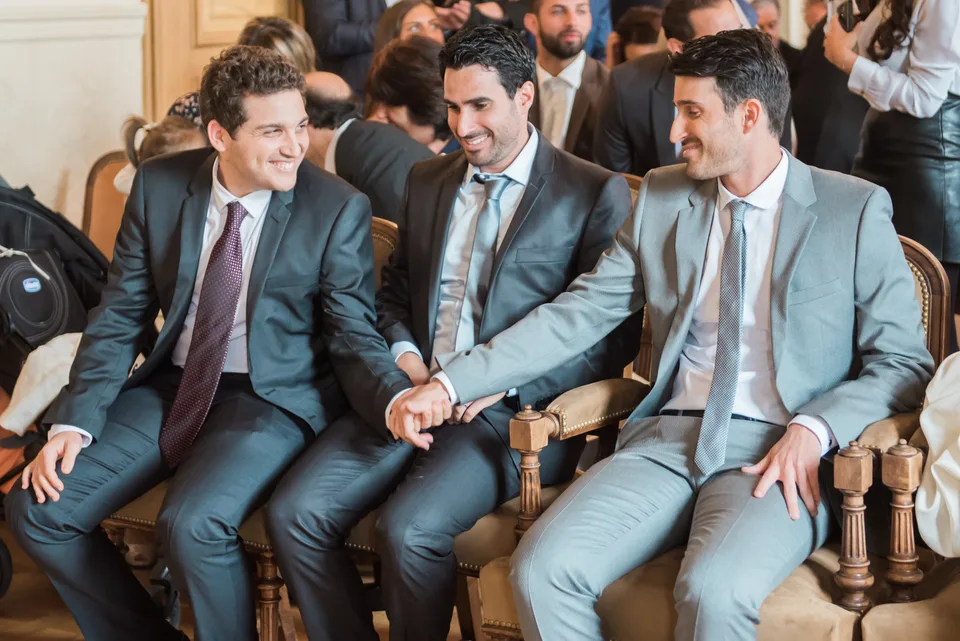 Three guests in suits talking on a sofa