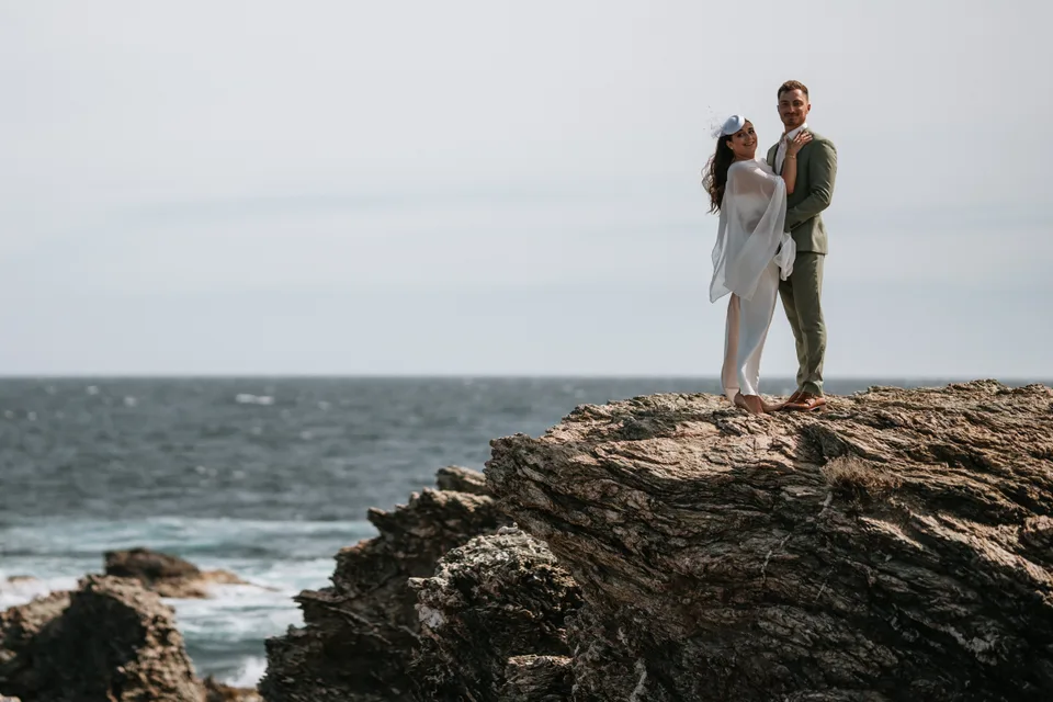 Newlyweds overlooking the sea from a rocky outcrop