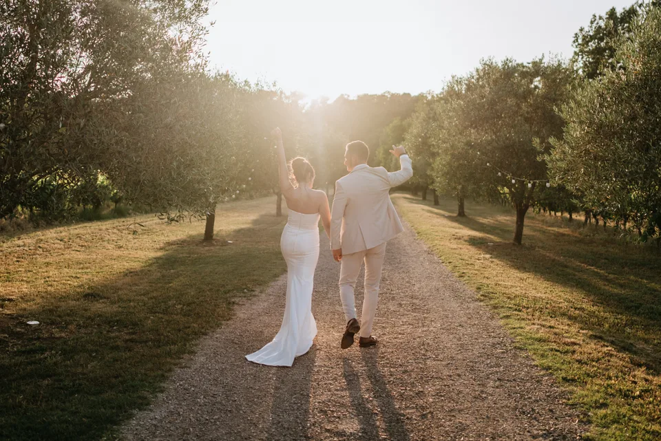 Newlyweds walking along a path at sunset