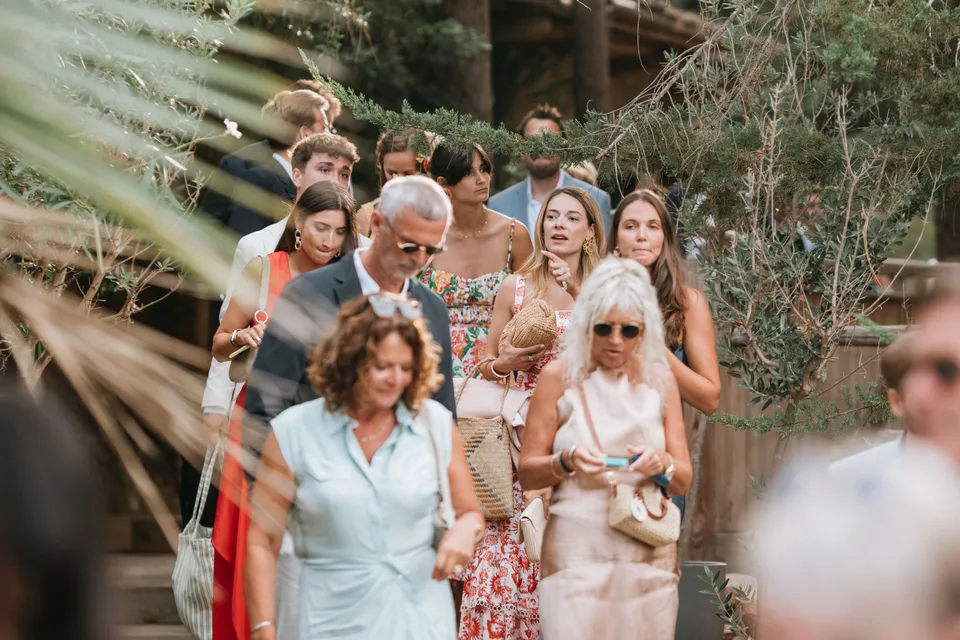 Guests following the wedding procession among the trees