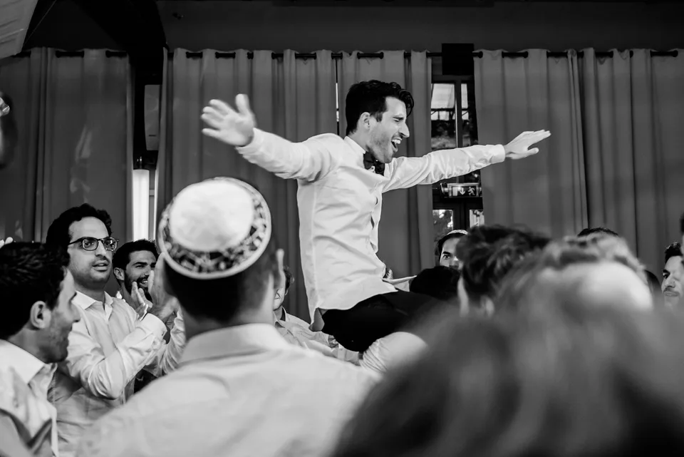 A guest with outstretched arms on the dance floor, in black and white