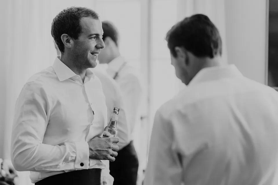 Two men sharing a moment during preparations, in black and white