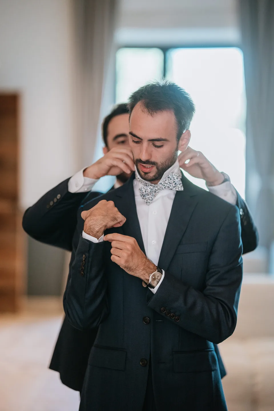 Someone adjusting the groom’s bow tie