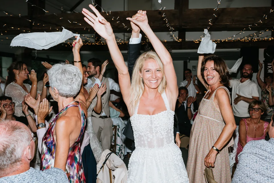 The bride and guests raising their arms during the party