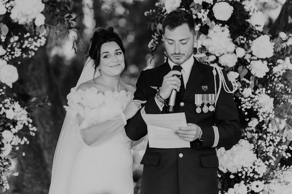 Newlyweds reading their vows in front of flowers