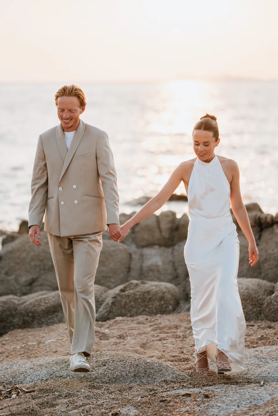 Newlyweds holding hands on the rocks