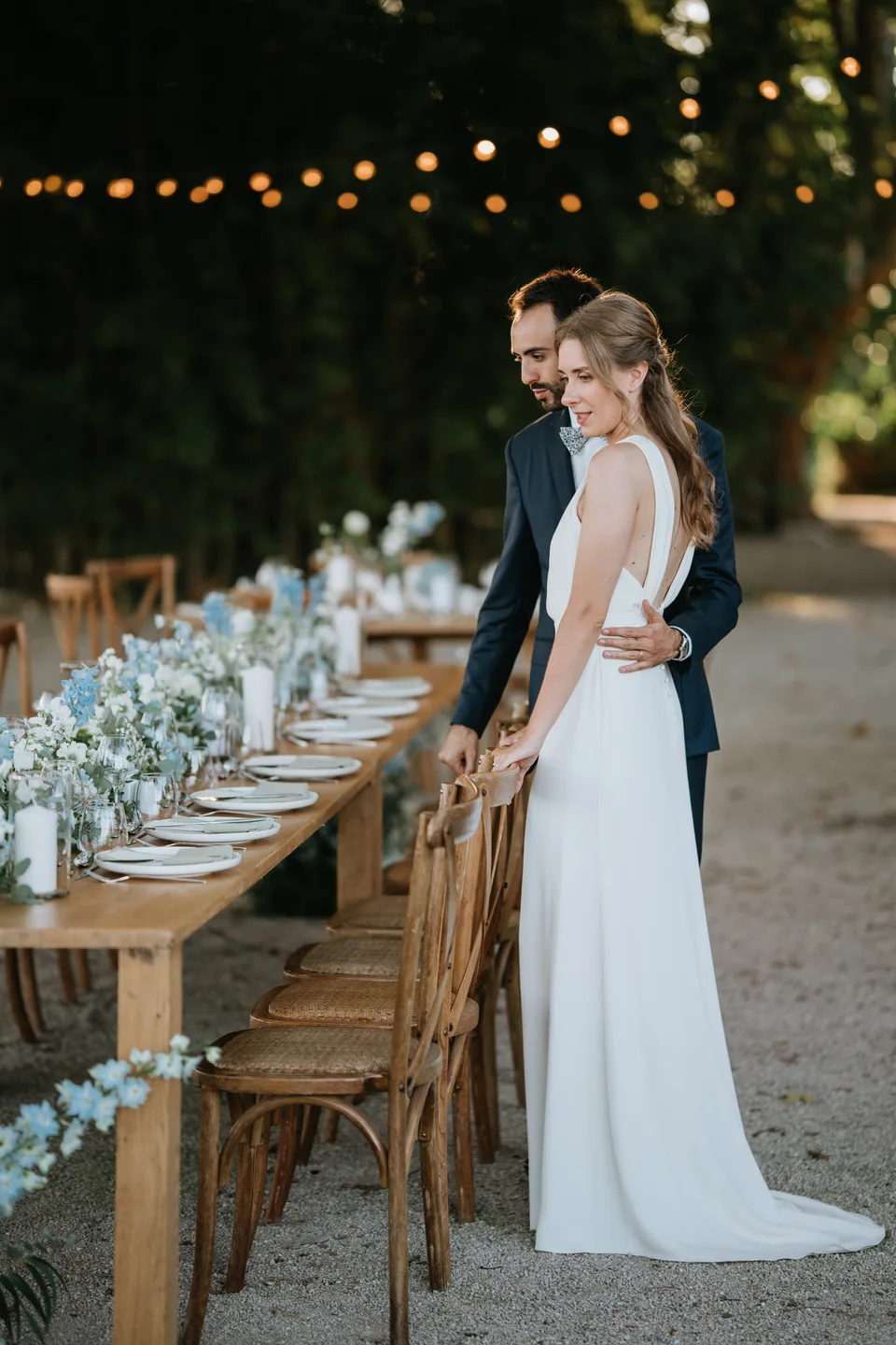 The bride beside a long table beneath string lights