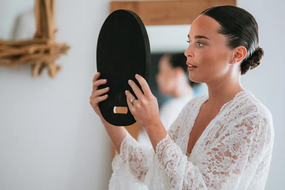 The bride checking her hair in a hand mirror