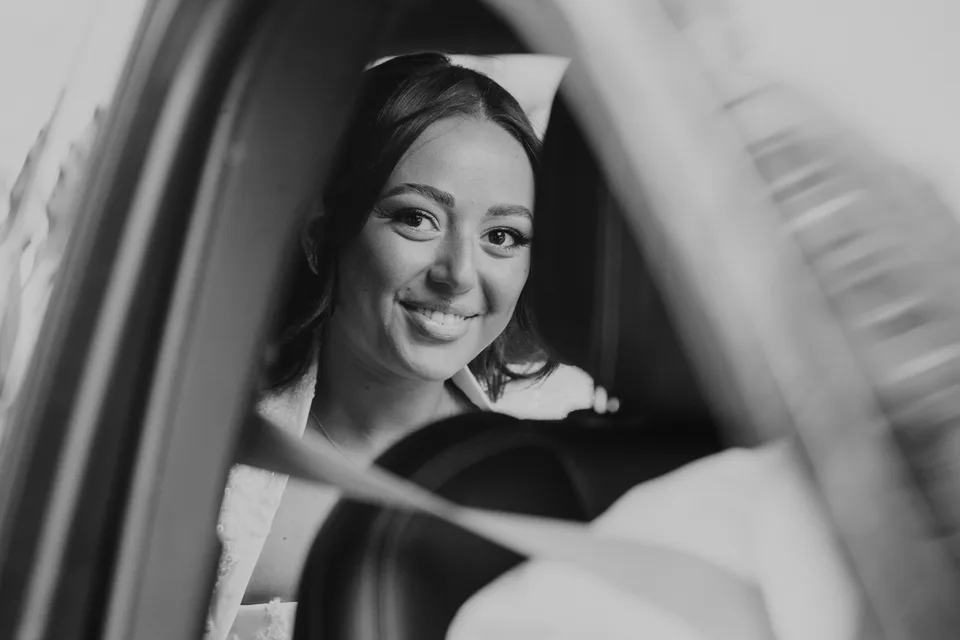 The bride smiling in a mirror, in black and white