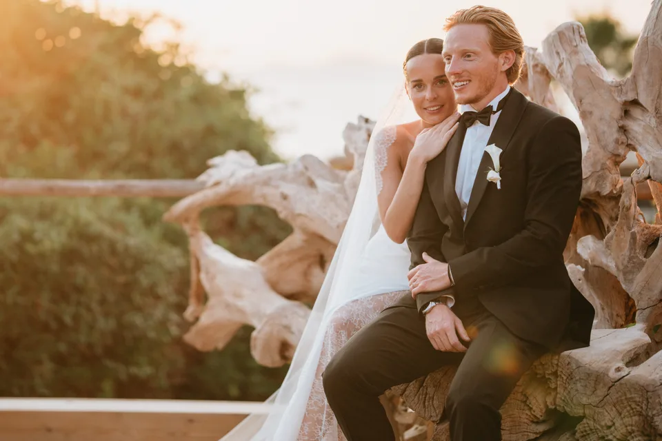 Newlyweds seated side by side at sunset