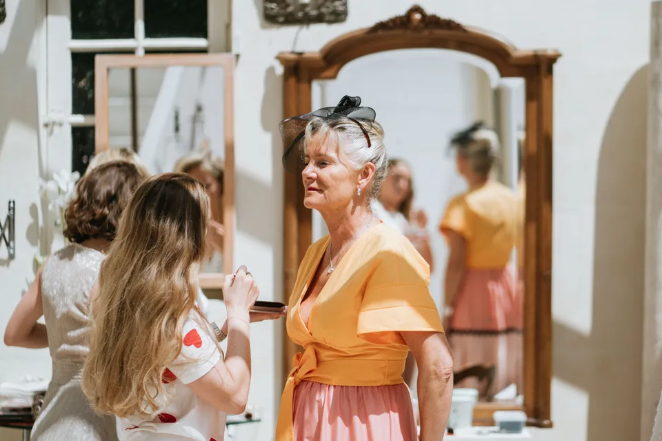 The bride talking with a loved one beside a mirror