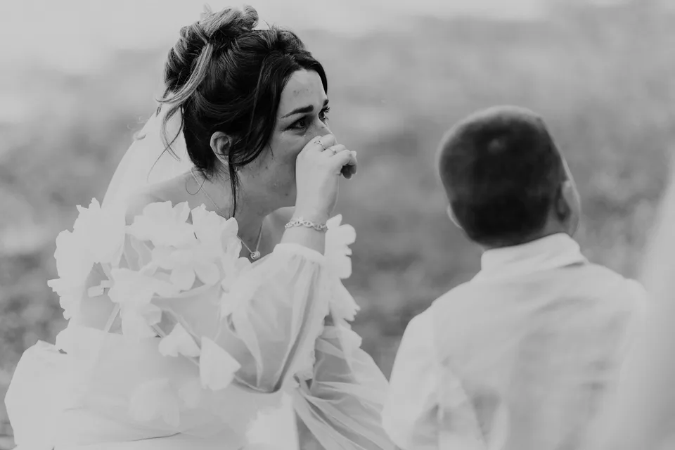The bride looking at her partner during the ceremony, in black and white