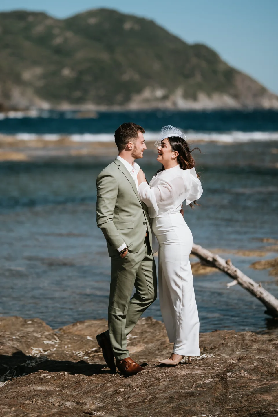 Newlyweds embracing on rocks beside the sea